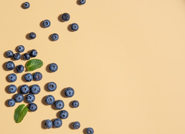 Blaubeeren und Minzblätter auf gelbem Hintergrund