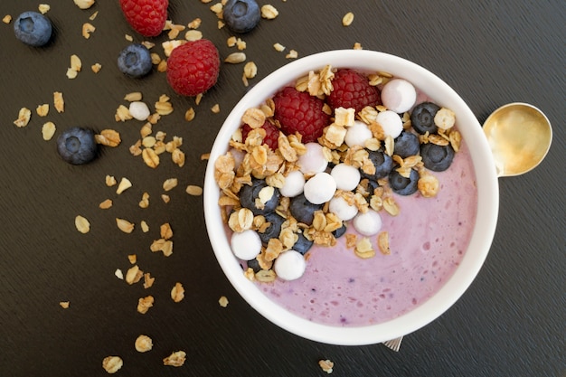 Blaubeerjoghurt mit frischen Beeren auf einem Holztisch.