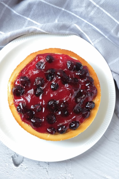 Blaubeerkäsekuchen in weißer Platte mit weißem Hintergrund