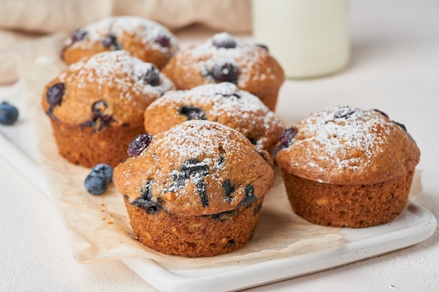 Blaubeermuffin, Seitenansicht, Abschluss oben. Kleine Kuchen mit Beeren auf weißer konkreter Tabelle, Frühstück