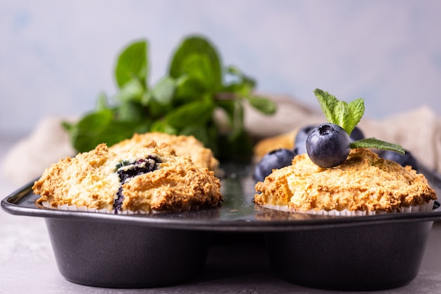 Blaubeermuffins mit frischen Beeren und tadellosen Blättern in der schwarzen Backform. Kopieren