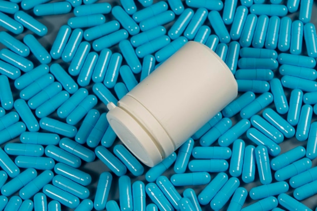 Blaue Antibiotika-Kapsel-Pillen-Textur mit weißer Flasche Pharmazeutische Produktion Globale Gesundheit Resistenz gegen Antibiotika-Medikamente Gelatine-Kapsel-Pillen