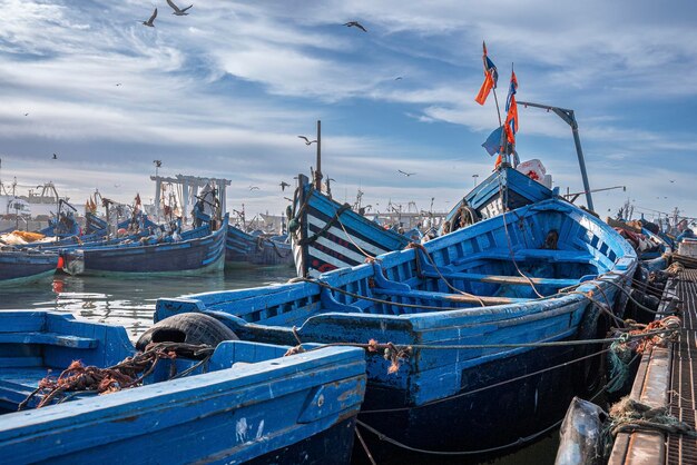 Blaue Fischerboote aus Holz, die am Jachthafen gegen bewölkten Himmel verankert sind