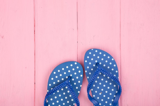 Blaue Flip-Flops in Polka Dots auf rosafarbenem Holzhintergrund
