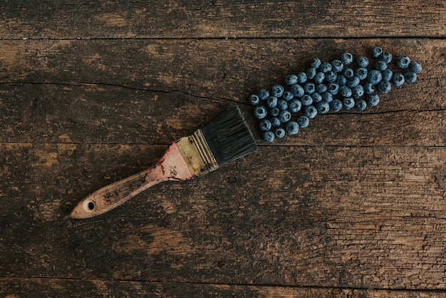 Blaue frische Blaubeeren sind auf einem alten braunen hölzernen rissigen Tisch verstreut