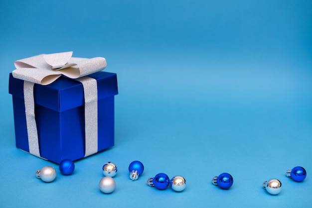 Blaue Geschenkbox mit Weihnachtskugeln auf einem blauen Hintergrundkopierraum