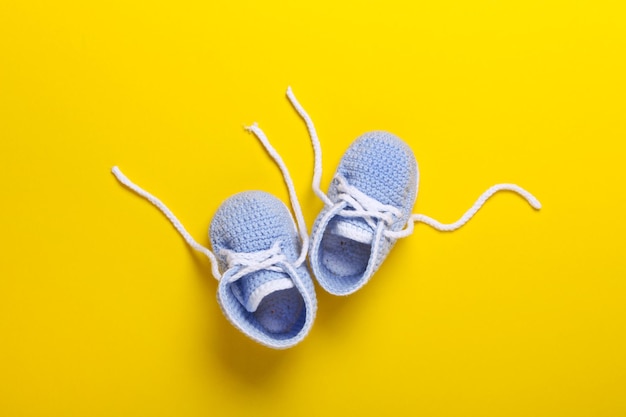 Foto blaue gestrickte babyschuhe auf gelbem hintergrund draufsicht flach liegend kopierraum