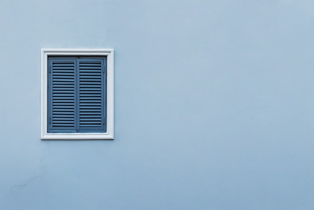 Blaue Hauswand mit geschlossenem Fenster links und Details.