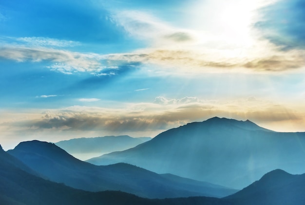 Blaue Hochgebirge und Sonnenuntergang strahlende Sonne