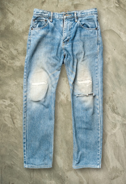Blaue Jeanshose auf grauem Schmutzboden