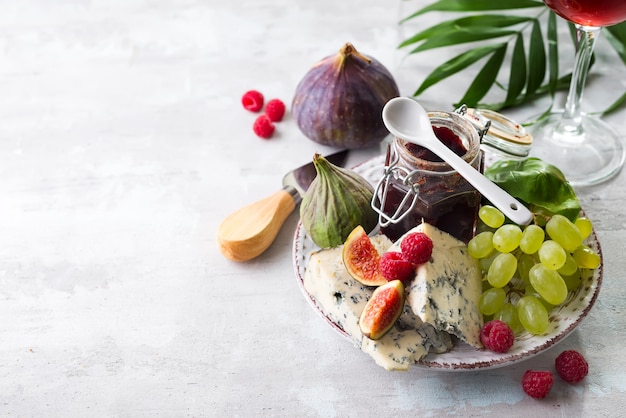 Blaue Käse, Frucht und Stau der Zartheit im Glas mit Palmblatt auf weißem Steinhintergrund, Kopienraum