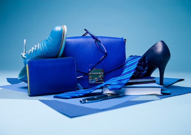 Blaue Komposition mit Schuh, Krawatte, Brille, Tasche, Stift und Notizbuch