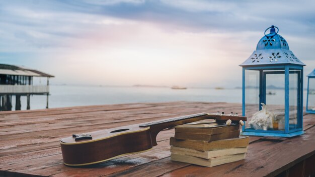 blaue Lampe Ukulele legen Holzboden Sonnenuntergang Meerblick Fischerdorf