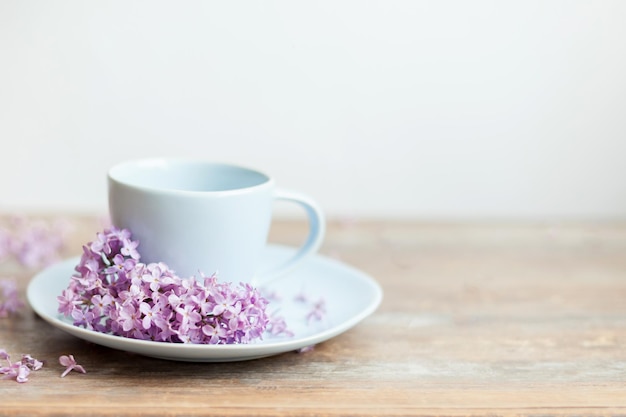 Blaue Morgenkaffeetasse mit Lilienblumen auf dem Holztisch. Inspirationsfoto der morgendlichen Routine