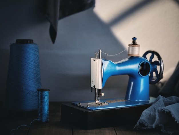 Blaue Nähmaschine mit Fäden auf dem Tisch