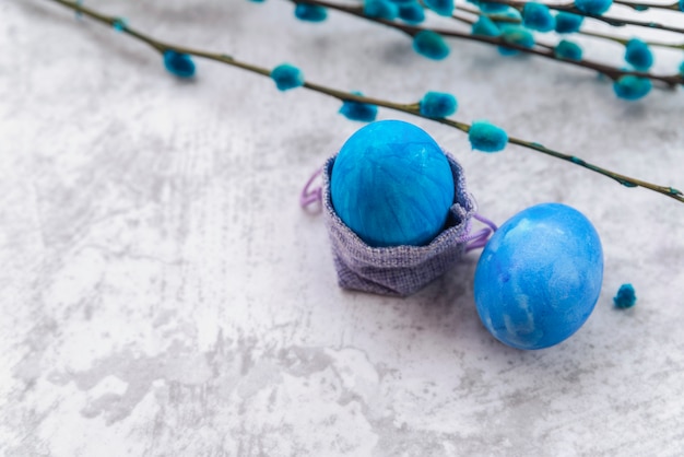 Blaue Ostereier mit dekorativen Taschen- und Weidenzweigen