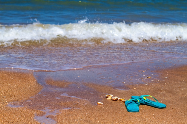 Blaue Pantoffeln stehen im Sand an der Küste