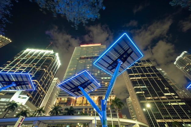 Blaue Photovoltaik-Solarmodule, die in der modernen Stadt auf Straßenmasten für die Stromversorgung von Straßenlaternen und Überwachungskameras montiert sind Futuristische Energiequelle in der Innenstadt von Miami, Florida