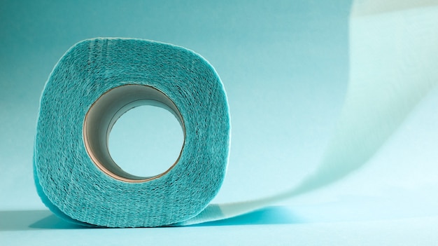 Blaue Rolle modernes Toilettenpapier auf blauem Hintergrund. Ein Papierprodukt auf einer Papphülle, verwendet für sanitäre Zwecke aus Zellstoff mit Ausschnitten zum leichten Aufreißen. Geprägte Zeichnung.