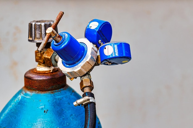 Blaue Sauerstoffflasche mit Wasserhahnventil und Manometergeräten Nahaufnahme von Gasschneidegeräten aus Metall