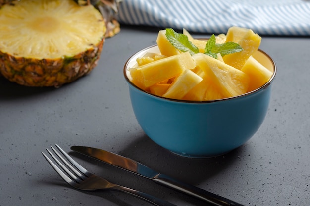 Blaue Schüssel mit frischer Ananas und Tischbesteck