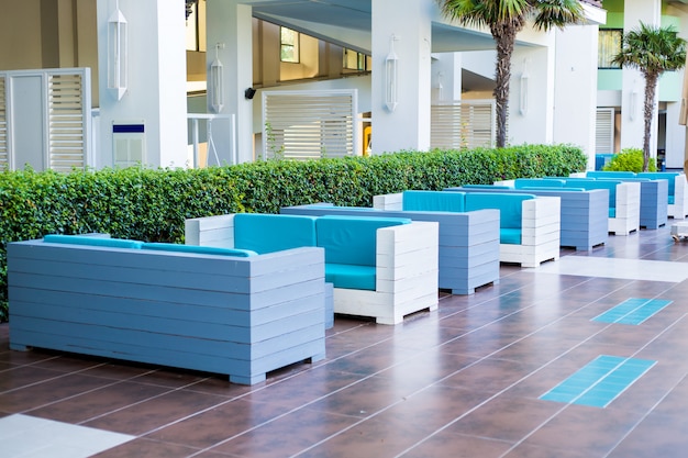 Blaue Sofas in einer Reihe im Freien im Lobbyhotel, eine Wand aus gepflegten Grünflächen