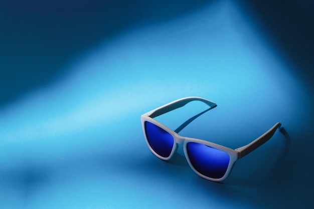 Blaue Sonnenbrille auf blauem Hintergrund mit Kopienraum. Studioaufnahme von Sonnenbrillen auf buntem Hintergrund