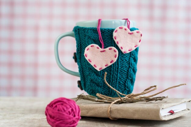 Blaue Tasse in einem blauen Pullover, der auf einem alten Notizbuch steht