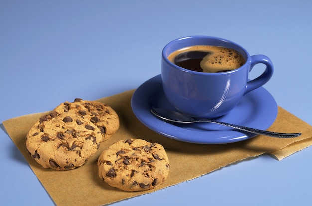 Blaue Tasse Kaffee und Schokoladenplätzchen auf dem Tisch