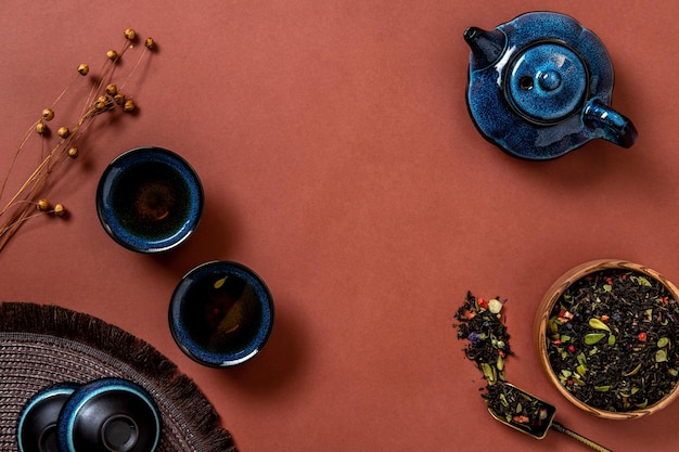 Blaue Teekanne Tasse Tee und Teeblätter auf braunem Hintergrund Heißer Kräutertee ist in der Teekanne auf dem Tisch Platz kopieren