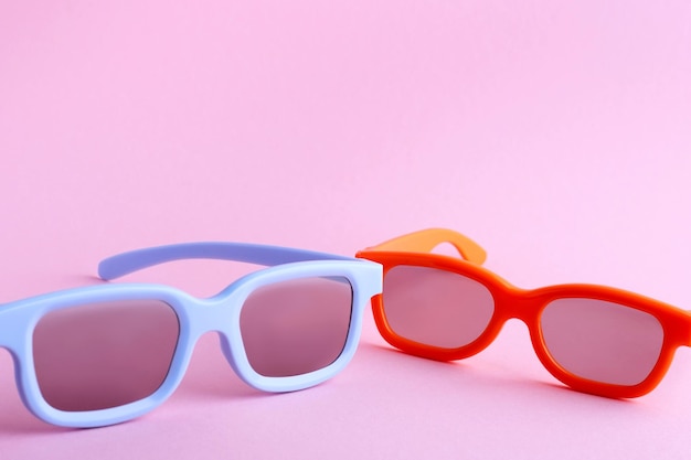 Blaue und orangefarbene 3D-Brille auf rosa Hintergrund Frontansicht von oben Die Brille ist nicht vollständig sichtbar