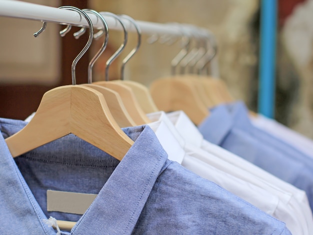 blaue und weiße Hemden, die am Gestell im Schrank hängen