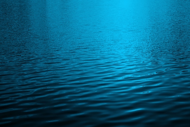 Blaue Wasseroberfläche mit hellen Lichtreflexionen des hellen Sonnenscheins
