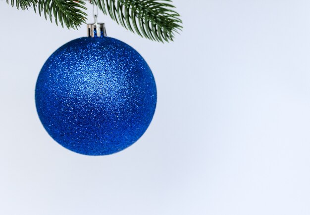 Blaue Weihnachtskugeldekoration, die auf Tannenzweig hängt