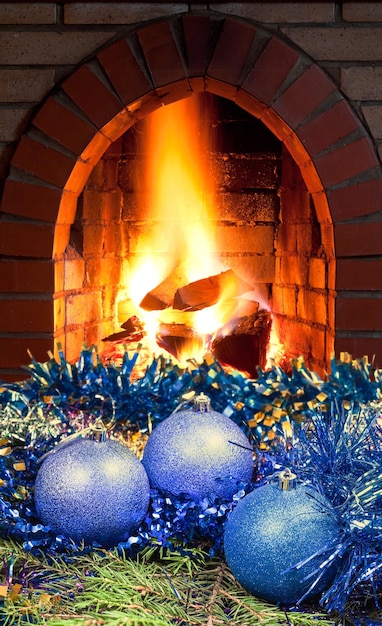 Blaue Weihnachtskugeln auf Fichte und Kamin