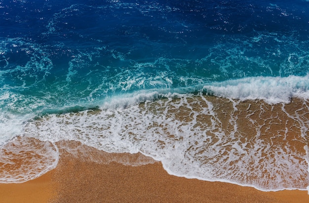 Blaue Welle am Strand. Unscharfer Hintergrund und Sonnenlichtflecken. Ruhiger natürlicher Hintergrund.