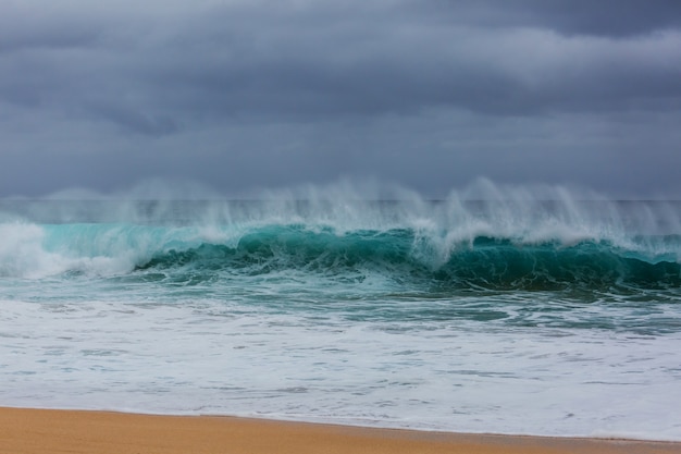 Blaue Welle am Strand. Verwischen Sie Hintergrund- und Sonnenlichtflecken. Friedlicher natürlicher Hintergrund.