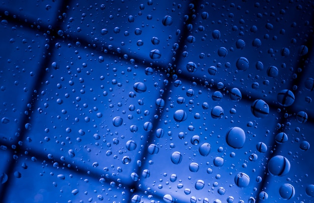 Blauer abstrakter Unschärfehintergrund mit Wasser fällt und Reflexion auf transparentem Glas. Blauer Hintergrund