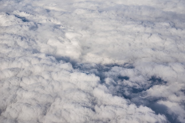 Blauer bewölkter Himmel, Blick vom Flugzeugfenster. Luftaufnahme der Wolkenlandschaft.