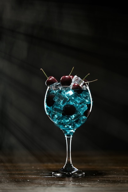 Foto blauer cocktail in einem glas mit eis und kirschen