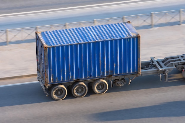 Blauer Containeranhänger, der mit hoher Geschwindigkeit auf einer Autobahn fährt.