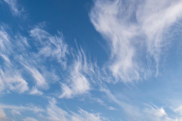 Blauer Himmelshintergrund mit großer, winziger, gestreifter Stratus-Zirruswolke