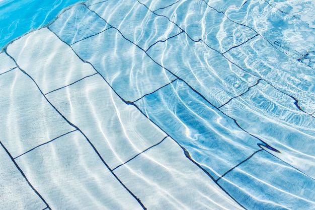 Blauer Hintergrund des Wasserpools mit Wasser plätschert an einem sonnigen Tag
