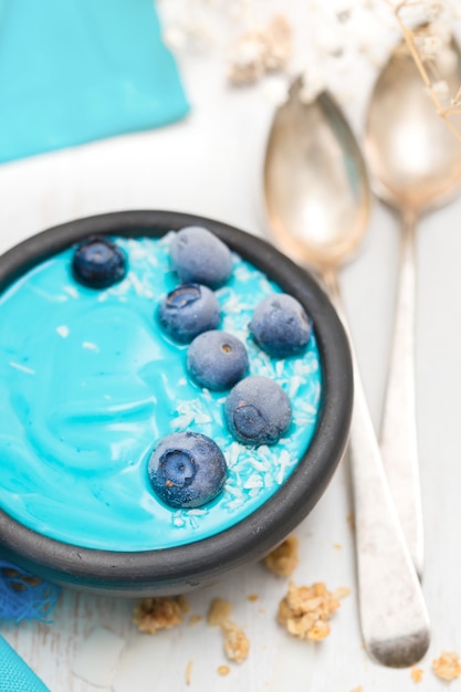Blauer Joghurt mit Beeren in der schwarzen Schüssel