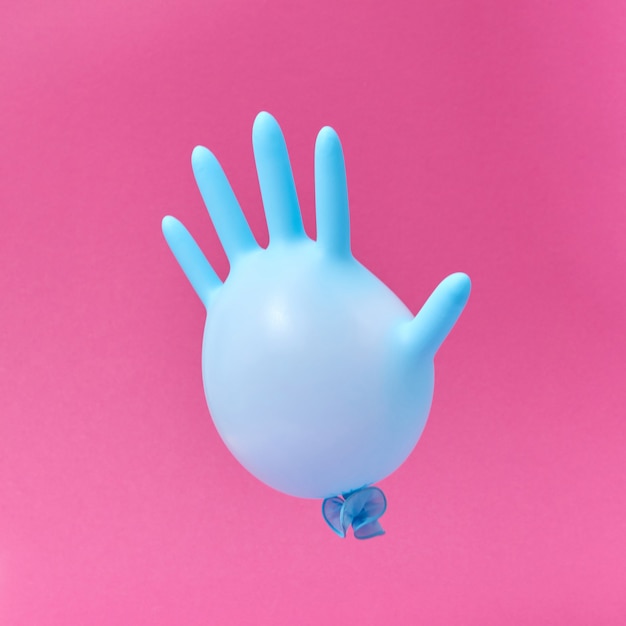 Blauer Latexhandschuhballon auf pinkfarbenem Hintergrund