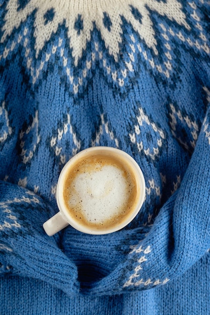 Blauer Pullover mit einer weißen, minimalistischen Tasse Kaffee mit Milch. Niemand lag flach.