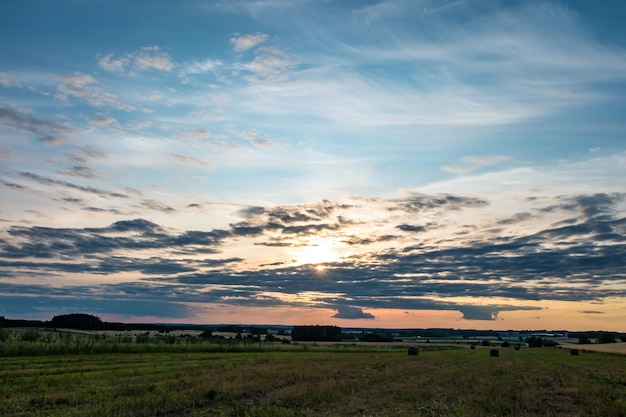 Blauer roter Himmelshintergrund mit flauschigen lockigen, rollenden Wolken am Abend mit untergehender Sonne Gutes windiges Wetter