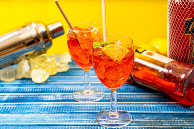 blauer Tisch mit zwei Gläsern des erfrischenden Aperol Spritz Cocktails mit Minze und Orangenblättern