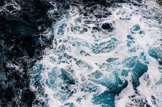 Foto blauer, türkisfarbener hintergrund des meereswassers mit weißen schaumwellen, top-view