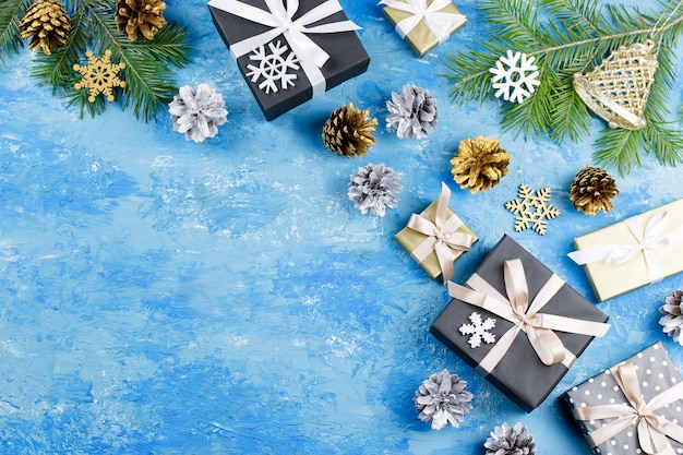 Blauer Weihnachtshintergrund mit Tannenzweigen, Geschenkboxen, silbernen und goldenen Dekorationen, Kopierraum. Ansicht von oben